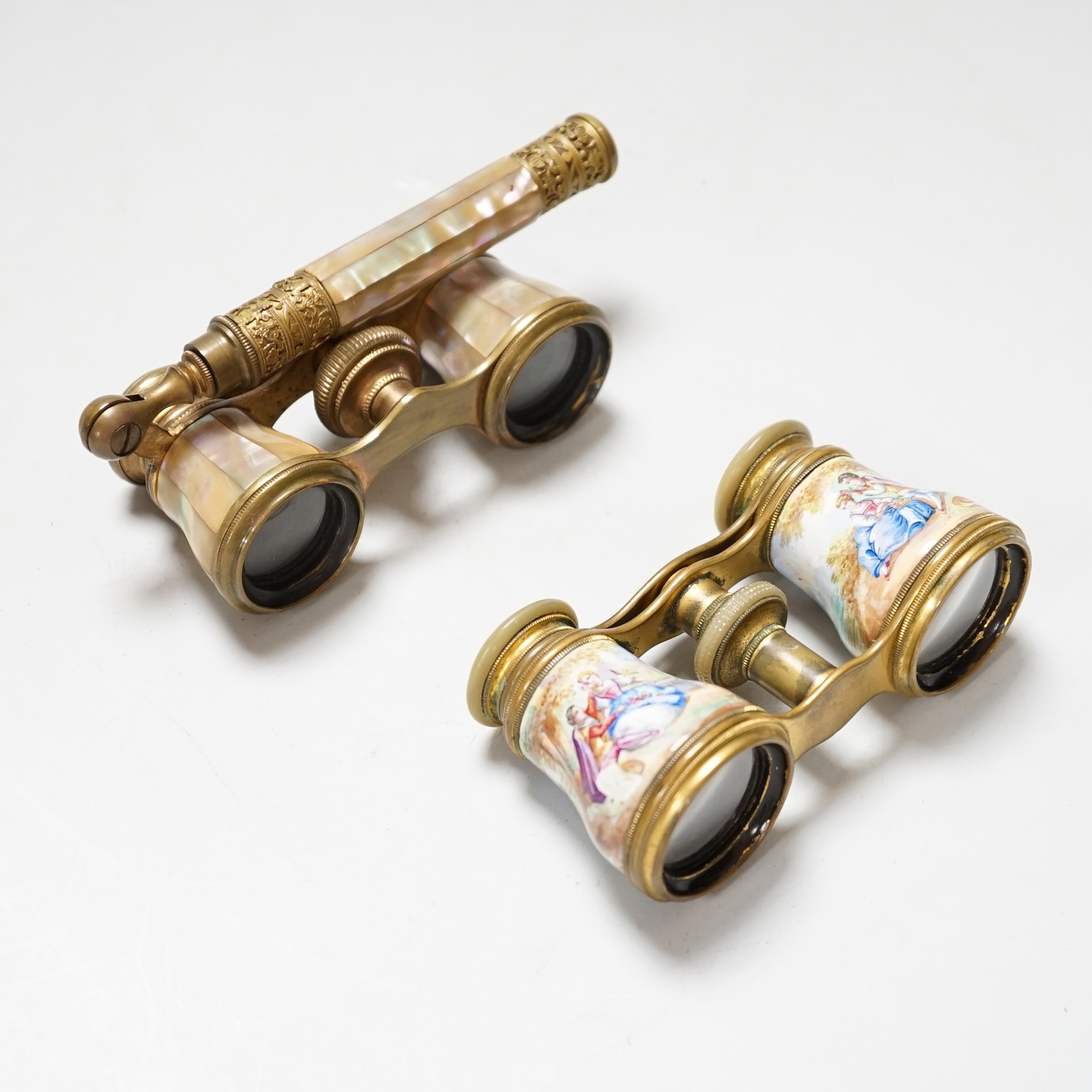 A pair of gilt brass and enamelled opera glasses and a similar pair of mother-of-pearl veneered opera glasses